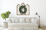Cathedral Wall Arch set with magnolia wreath in a living room setting with couch. 