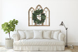 Cathedral Wall Arch set with magnolia wreath in a living room setting with couch.