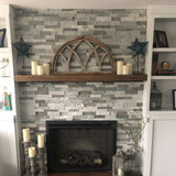 Gray half moon window on mantle with candles over fireplace.